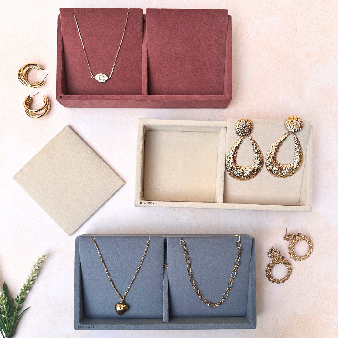 2-slot necklace and earring organiser trays in dark pink, cream, and grey velvet with jewelry displayed.