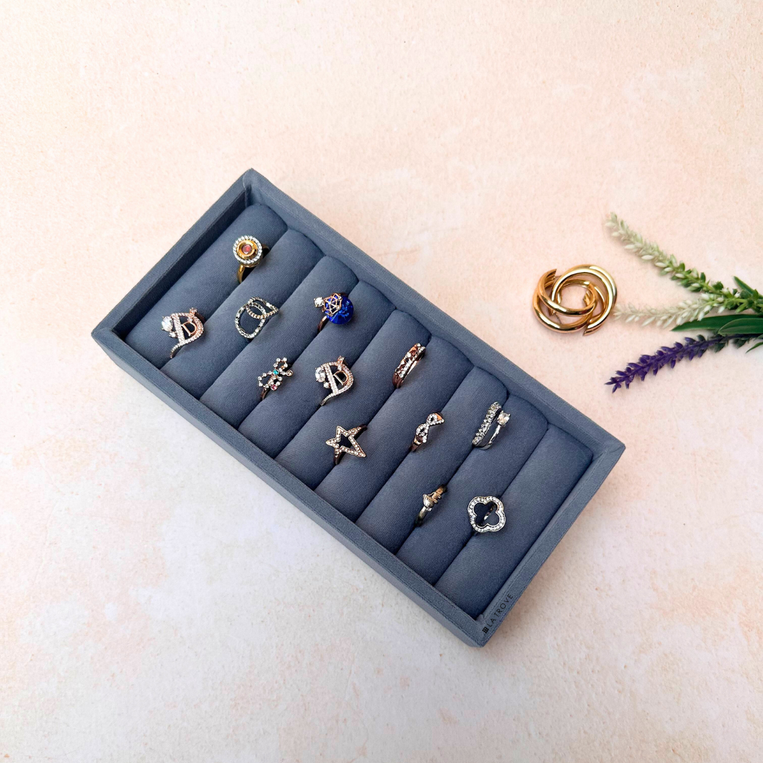 Grey ring display tray with velvet rows for elegant ring and stud arrangement.