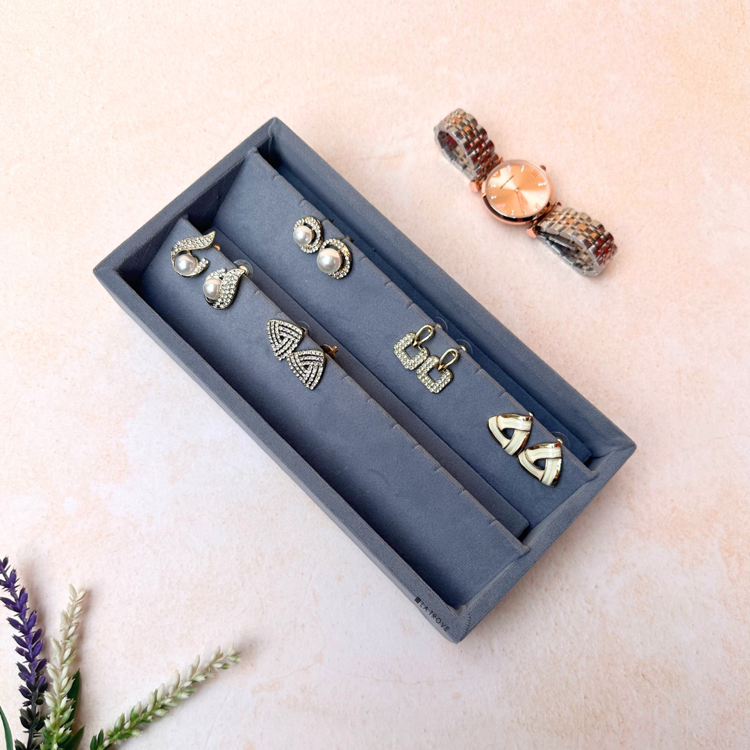 Grey earring organiser tray with cushioned velvet surface and dedicated slots.