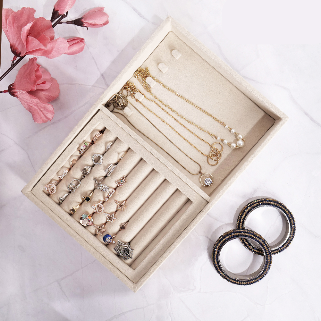 Cream velvet tray for storing rings and chains in separate sections.