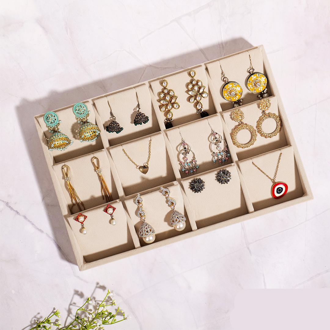Cream velvet earrings jewellery tray with compartments for studs and hoops.