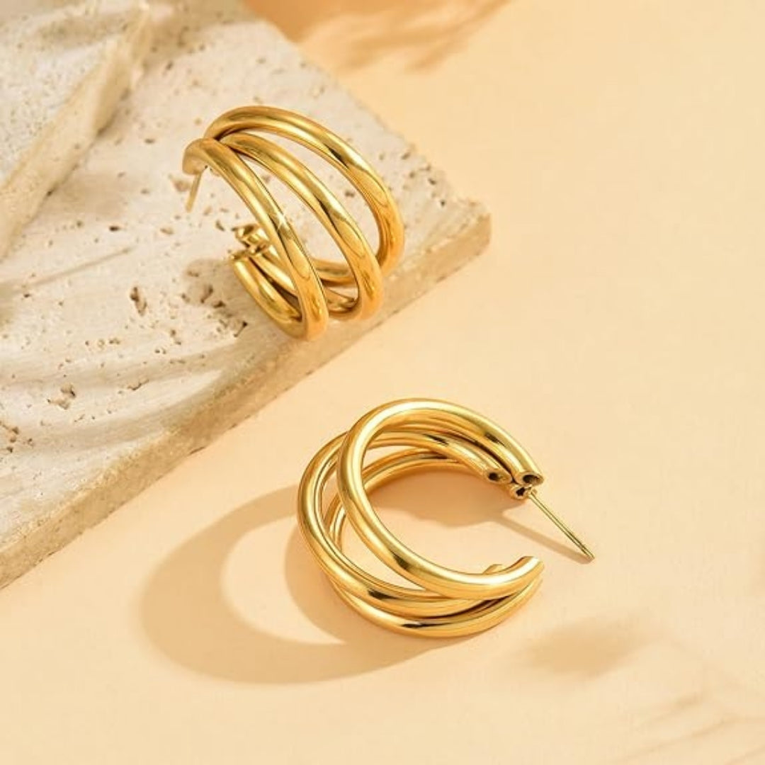 Triple layered gold hoop earrings on white background.